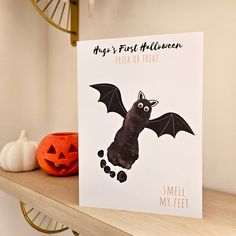 a card with a bat on it sitting on top of a shelf next to a pumpkin