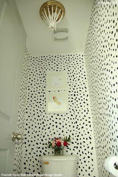 a white toilet sitting in a bathroom next to a wall with black dots on it