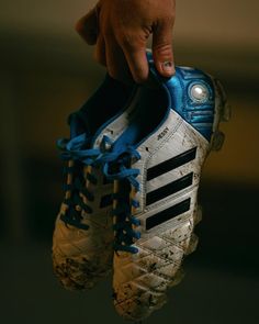 a person holding up a pair of soccer shoes