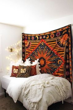 a bed with pillows and blankets on top of it next to a wall mounted light