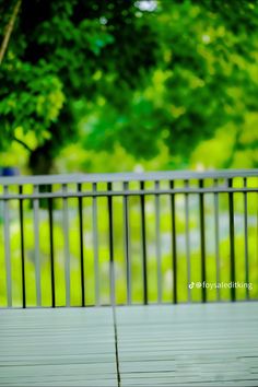 an umbrella sitting on top of a wooden deck next to a green park filled with trees