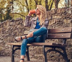 a woman sitting on a bench holding a drink