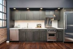 an empty kitchen with stainless steel appliances and wood floors