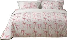 a bed with pink bows on it and two pillows in front of the headboard