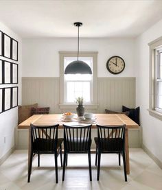 a dining room table with four chairs and a clock on the wall