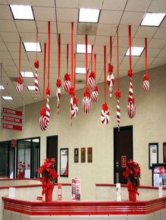 red and white ornaments hanging from the ceiling in an office building with christmas decorations on it