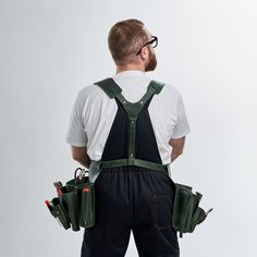 a man in overalls and safety glasses is holding two tool pockets on his back