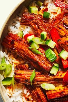 a bowl filled with rice, meat and veggies next to sliced cucumbers