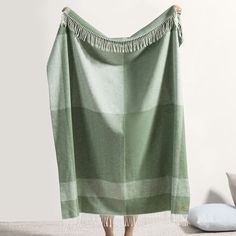 a person holding up a green and white blanket