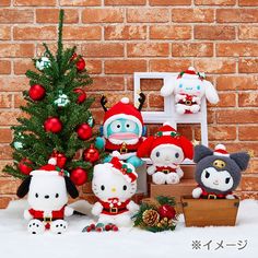 hello kitty christmas decorations are displayed in front of a brick wall with a small tree