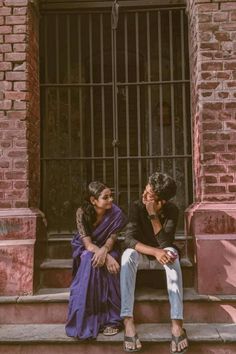 two people sitting on the steps in front of a building with bars and barred windows