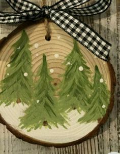 a piece of wood with some green trees painted on it and a bow hanging from the top