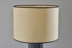 a lamp that is on top of a table with a black base and beige shade