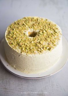 a cake with white frosting and green sprinkles on top sitting on a plate