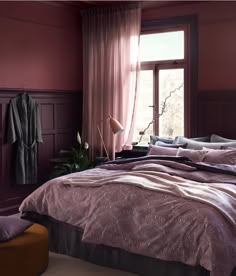 a bedroom with pink walls and purple bedding in the corner, along with a large window