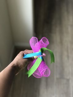 a person is holding a pink and green pinwheel