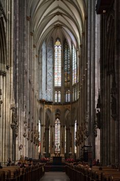 the inside of a large cathedral with pews and stained glass windows on both sides