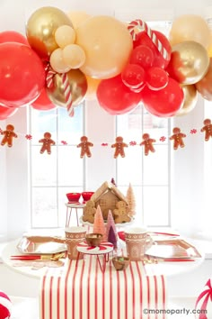 a table topped with lots of balloons next to a gingerbread house and christmas decorations