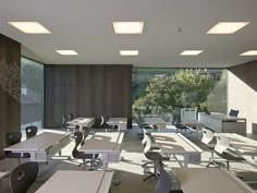 an empty classroom with desks and chairs in the middle, facing out to trees