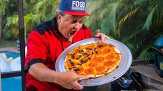 a man holding a pizza on top of a pan