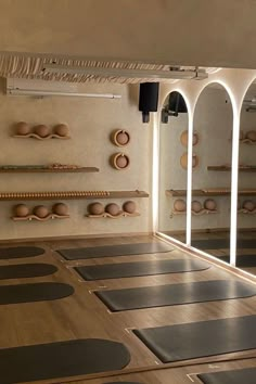 yoga mats are lined up on the floor in front of an arched doorway with mirrors