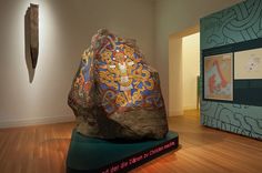 a large rock sitting on top of a wooden floor next to a wall with paintings