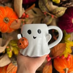 a hand holding a coffee cup with a ghost face on it