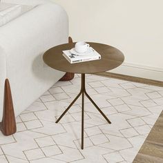 a coffee table with a book on it in front of a white couch and wooden legs