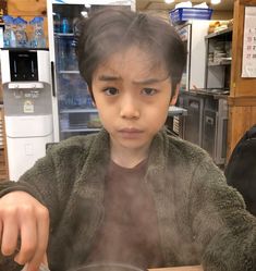 a young boy sitting at a table with food in front of him