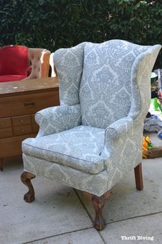 a blue and white chair sitting on top of a cement floor next to a wooden dresser