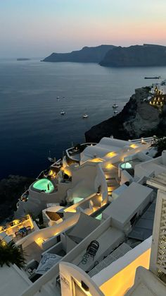 an aerial view of the ocean and buildings at dusk with boats in the water behind them