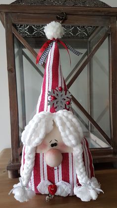 a stuffed animal wearing a red and white striped santa claus hat on top of a wooden table