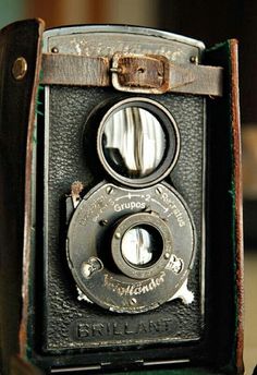 an old fashioned camera sitting on top of a green chair with the lens facing up