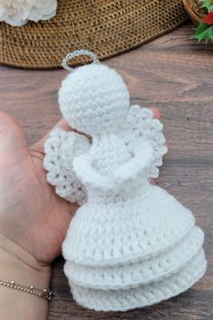 crocheted angel ornament being held by someone's hand on a table