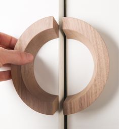 a person is holding the edge of a wooden object with one hand and another hand reaching for it