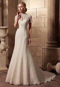 a woman in a white wedding dress standing next to a stone wall with columns and pillars