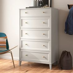 a white chest of drawers next to a blue chair