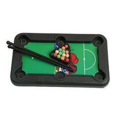 a pool table with some balls and cues on the green surface in front of it