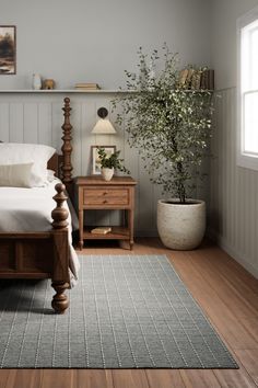 a bed sitting in a bedroom next to a wooden dresser and table with a plant on top of it