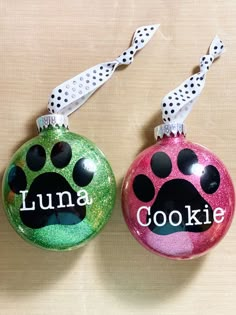 two christmas ornaments with paw prints and the words lunaa cookie written on one ornament