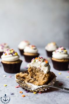 cupcakes with white frosting and sprinkles are on a table