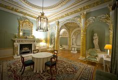 an ornate dining room with green walls and gold trimmings, including a chandelier