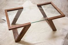 a glass and wood coffee table on top of a white furnishing area with an animal skin rug