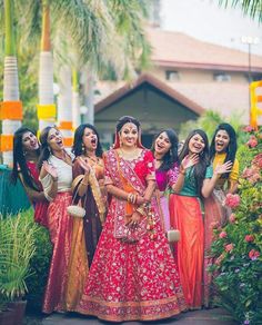 a group of women standing next to each other in front of some trees and flowers