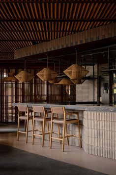 an empty bar with wooden stools and lamps hanging from the ceiling in front of it