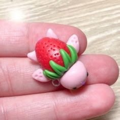 a hand holding a tiny toy with a strawberry on it