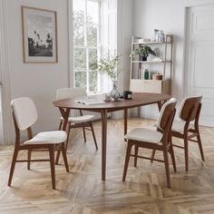 a dining room table and chairs with wood flooring in front of a large window