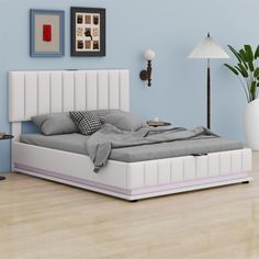 a white bed sitting on top of a hard wood floor next to a blue wall