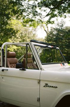 an old white truck parked in front of trees