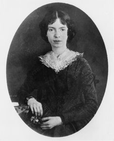 an old black and white photo of a woman wearing a lace collared dress, holding a small object in her right hand